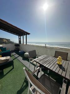 a patio with a table and chairs and the ocean at Fonte da Telha Beach Hostel in Costa da Caparica