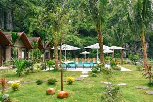 a resort yard with a pool and tables and umbrellas at Tam Coc Aurora Valley in Vũ Lâm