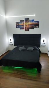 a bedroom with a black bed with four pictures on the wall at Relax Rooms in Trapani
