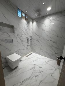 a white bathroom with a toilet and marble walls at Hotel Krishna Leela Lodging and Boarding in Bhusāwal