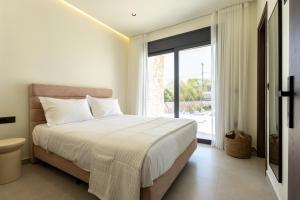 a bedroom with a bed and a large window at Noera Villas in Kremasti +80 photos