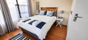 a bedroom with a large bed with blue and white pillows at Honey Cove in Mossel Bay
