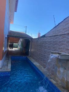 a swimming pool next to a brick wall with a water fountain at Pousada Encanto De Itanhaém in Itanhaém