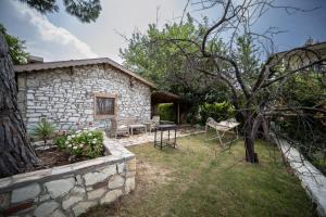 a stone cottage with a table and chairs in a yard at Dutlu Konak Taş Evleri in Soğucak