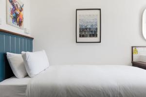a bedroom with a white bed with a picture on the wall at Southern Cross in Watford