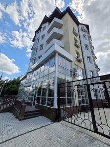 a tall building with glass windows and a fence at Prestige Apartment in Mykolaiv