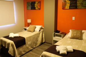 a room with two beds and an orange wall at Savannah Cordoba Hotel in Córdoba