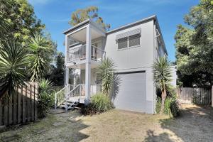 a white house with a garage and palm trees at Flip Flop Inn in Amity Point