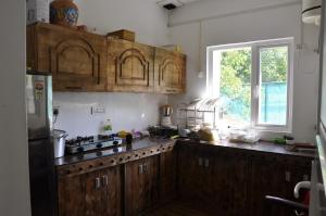 a kitchen with wooden cabinets and a window at VELORA-DOODHPATHRi in Aphit