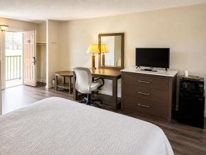 a hotel room with a bed and a desk with a television at Country Host Inn in Franklin