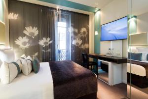 パリにあるグラン ホテル サン ミッシェルのベッドとデスクが備わるホテルルームです。