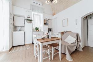 a white kitchen with a wooden table and chairs at A L Tourist House - La Corte di Cavuor in Monopoli