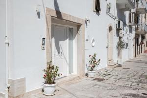 a white building with a door and two potted plants at A L Tourist House - La Corte di Cavuor in Monopoli