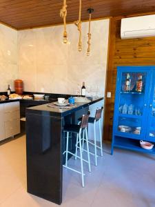 a kitchen with a bar with stools and a blue cabinet at Chalé Saúde in Venda Nova do Imigrante