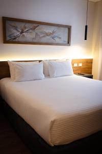 a large bed with white sheets and pillows at Dazzler by Wyndham Salta in Salta
