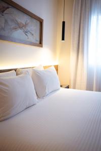 a white bed with white pillows and a window at Dazzler by Wyndham Salta in Salta