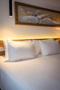 a bed with white pillows and a painting on the wall at Dazzler by Wyndham Salta in Salta