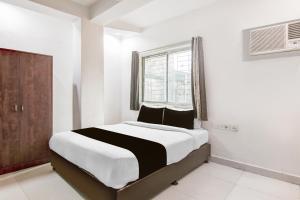 a bedroom with a bed with white walls and a window at Hotel O CITY INN in Kolkata