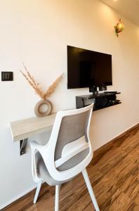 a white chair sitting in front of a desk with a tv at Luxury Apartment With Farm View in Siolim