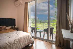 a bedroom with a bed and a balcony with a view at Luxury Apartment With Farm View in Siolim