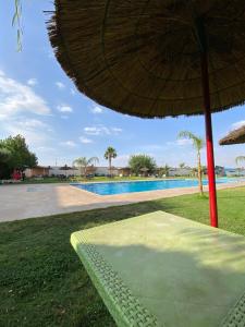 a table with an umbrella next to a swimming pool at La ferme labyed in Fez +9 photos