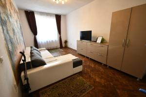 a living room with a white couch and a television at Mural Art Apartament in Petroşani