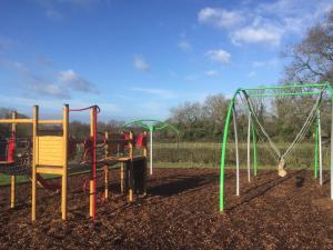 a playground with several different types of swings at Hunters Lodge Inn in Wincanton