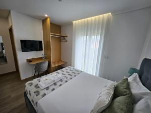 a bedroom with a bed and a desk and a television at DiROMANE in Braga