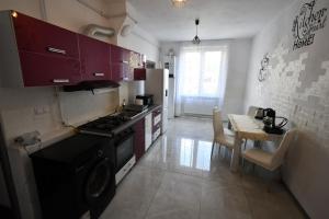 a kitchen with a stove and a table with chairs at Mural Art Apartament in Petroşani