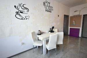 a white dining room with a table and white chairs at Mural Art Apartament in Petroşani +4 photos