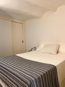 a white bed with a black and white striped blanket at Tu mejor estadia en Tarragona centro in Tarragona