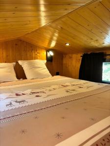 a bed in a room with a wooden ceiling at Tiny house chalet montagnard in Arcizans-Dessus