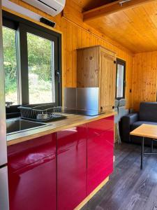a kitchen with red cabinets and a sink at Tiny house chalet montagnard in Arcizans-Dessus