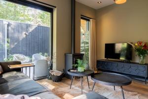 a living room with a couch and a tv at Boshuis midden in het bos met houtkachel in Appelscha in Appelscha