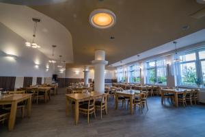 a dining room with tables and chairs and windows at Hotel Churáňov in Stachy