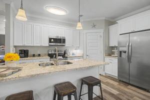 a kitchen with white cabinets and a stainless steel refrigerator at 3BD Beach House by Next Step Property Management in Long Beach