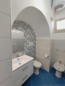 a white bathroom with a sink and a toilet at L'Eco del Mare in Pisciotta