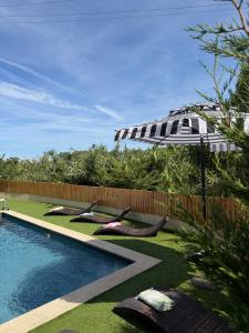 a pool with lounge chairs and an umbrella next to a fence at Azurara Guesthouse in Azurara