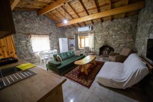 a living room with a green couch and a stone wall at Dutlu Konak Taş Evleri in Soğucak