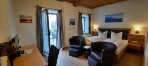 a hotel room with a bed and chairs and a television at Hotel Pension Lindenhof in Prien am Chiemsee