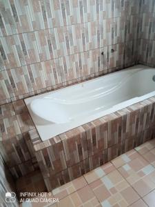 a bath tub in a bathroom with a tiled floor at Hôtel Maximum in Agbézourhlan