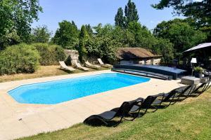 a swimming pool with chairs and an umbrella at la bonbonniere in Saunay