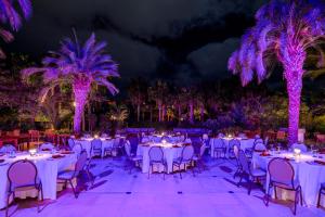 a banquet hall with white tables and palm trees at night at Hilton Cabo Verde Sal Resort in Santa Maria +176 photos