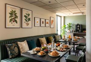 a table with plates of food on it in a restaurant at APARTÉ HOTEL Dijon Sud in Chenôve