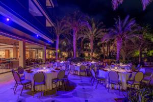 a banquet hall with white tables and chairs and palm trees at Hilton Cabo Verde Sal Resort in Santa Maria