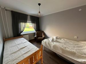 a bedroom with a bed and a chair and a window at Viskoosa Näkmani Apartment in Kõrgessaare