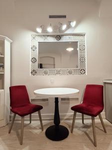a table with two red chairs and a mirror at Alandala Story in Cluj-Napoca