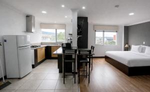 a kitchen and a bedroom with a bed and a kitchen and a refrigerator at Gaviota Apartments & Suites in Cuenca