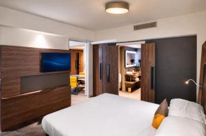a hotel room with a bed and a flat screen tv at Rénéa Hotel in Sétif