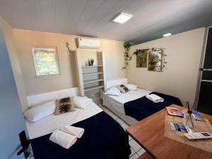 a room with two beds and a table at Pousada Vilas do Frances Beira Mar in Praia do Frances